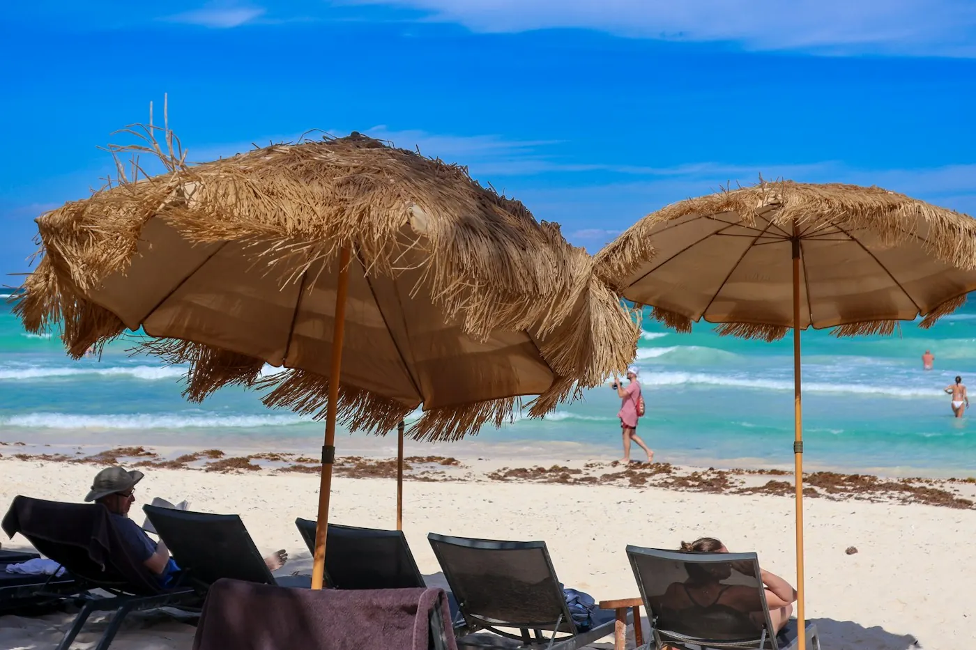 Thatched umbrellas and loungers beside the sea in Tulum